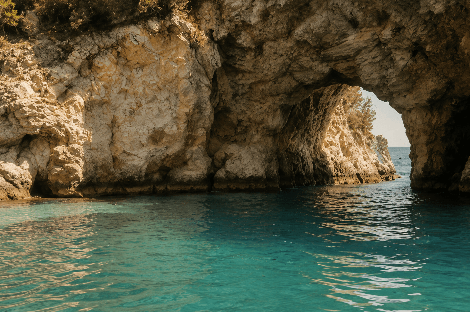 Sea cave with a turquoise pool, viewed through a natural rock arch