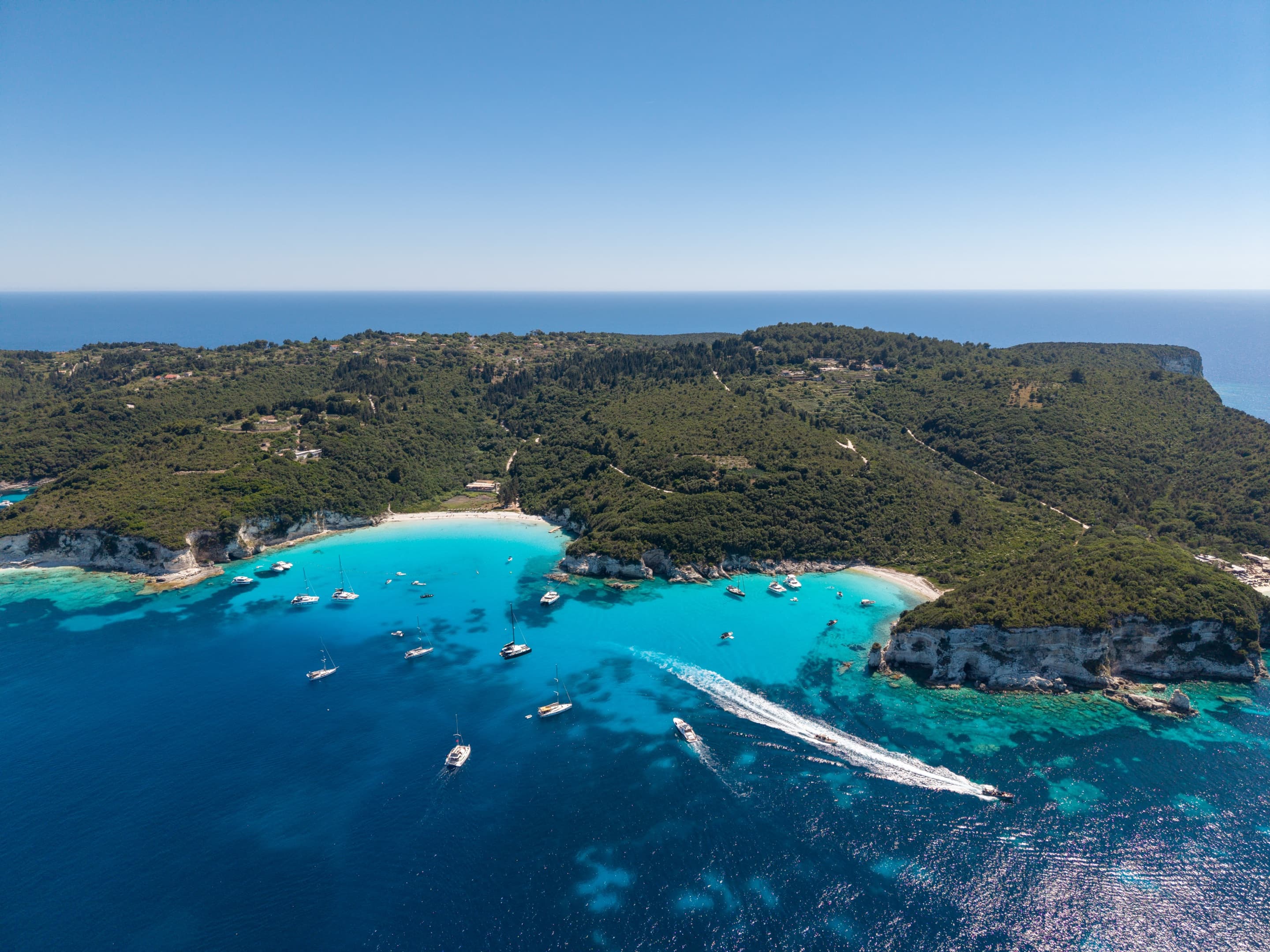 Αεροφωτογραφία ενός τιρκουάζ όρμου των Παξών με ιστιοπλοϊκά